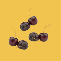 Fresh black cherries on a warm yellow background representing Wild Desert SUGAR FREE | Dye-FREE Black Cherry Coffee Syrup. Bold, sweet, and tart flavor. FREE & Clear, sugar free, keto-friendly, crafted with organic monk fruit & erythritol.