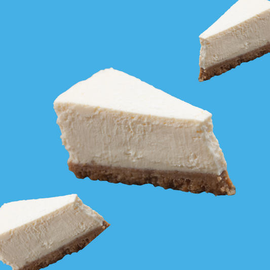Slice of cheesecake on a vibrant sky blue background representing Hypothermias Cheesecake SUGAR FREE | Dye-FREE Snow Cone Syrup. Creamy dessert flavor, sugar free, dye free, keto-friendly with monk fruit & erythritol.