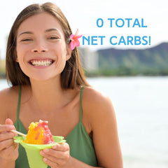 Woman enjoying shaved ice dessert by the ocean and mountains. Sugar Free & Dye-FREE shaved ice syrup with 0 total net carbs, made with organic monk fruit and erythritol. Perfect for frozen treats and summer refreshment.