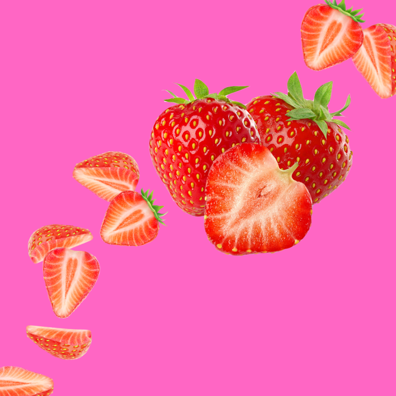 Fresh strawberries on a vibrant pink background representing Hypothermias Strawberry Sugar Free Dye-FREE Slush Syrup, a keto-friendly slush mix with zero net carbs for slush machines and frozen drinks