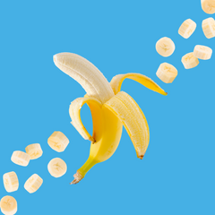 Fresh bananas on a vibrant sky blue background representing Hypothermias Banana SUGAR FREE | Dye-FREE Shaved Ice Syrup. Zero net carbs, sugar free, dye free, keto-friendly syrup made with monk fruit and erythritol.