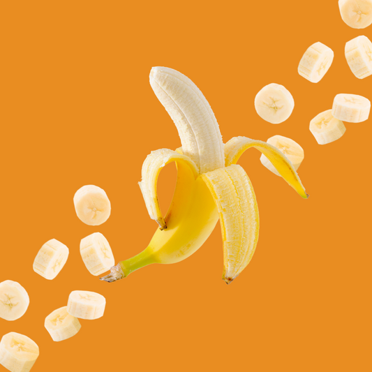 Banana and banana slices on a burnt orange background representing Wild Desert Dye-FREE Banana Coffee Syrup. Made with non-GMO 100% pure cane sugar and crafted in small batches by a family-owned business in Tucson, Arizona. Sweet, creamy banana flavor adds tropical taste to coffee, lattes, teas, smoothies, and specialty drinks.
