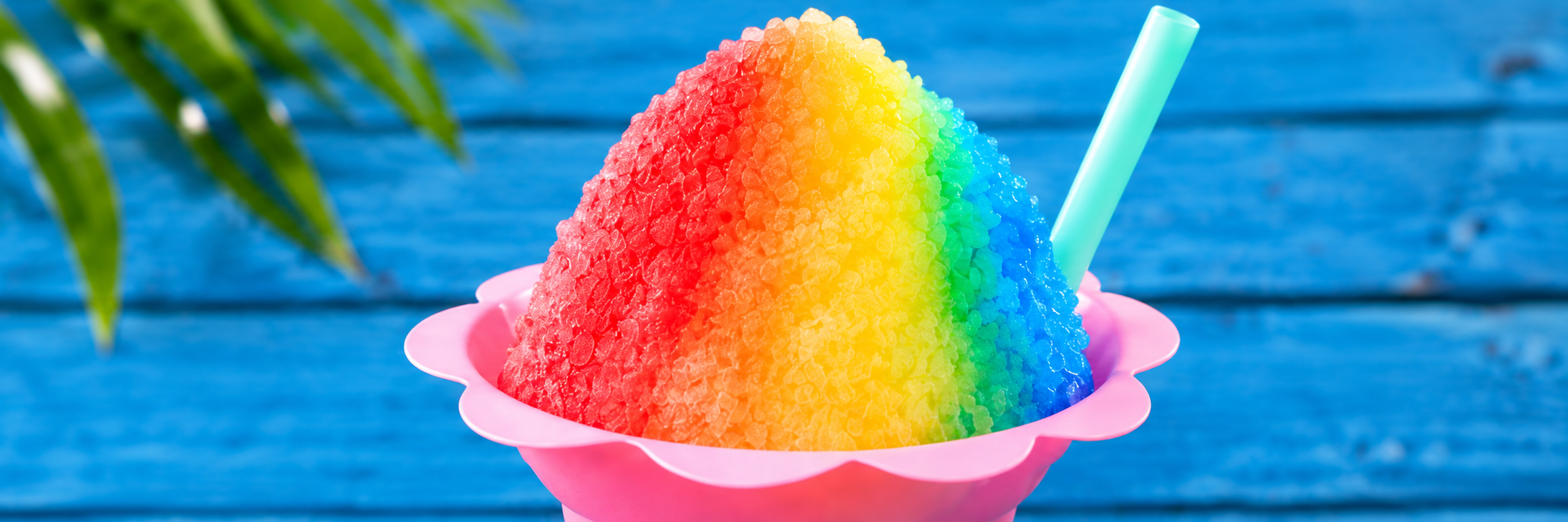 Rainbow shaved ice with colorful syrup in a pink flower cup